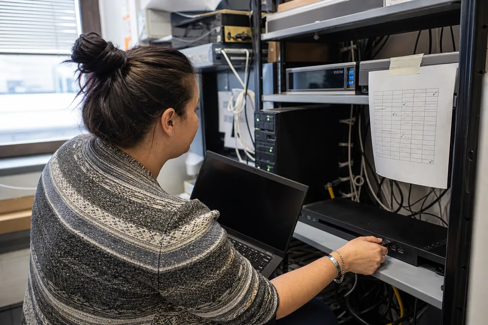 IT administrator at a small office server cupboard with a printed weekly schedule